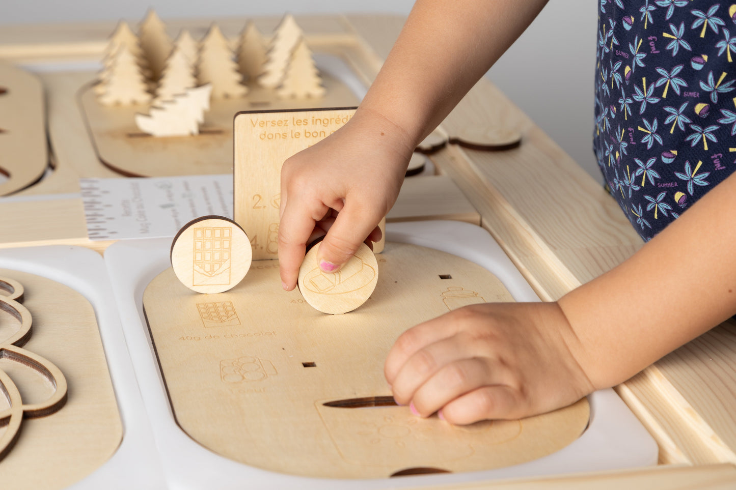 Enfant jouant avec la planche recette Montessori Le Mugcake, manipulant les pièces en bois représentant les ingrédients