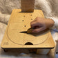 Main d’un enfant insérant une pièce en bois dans une planche Montessori avec des instructions gravées, montée sur un support robuste.